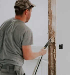 Man repairs a door with a crow bar